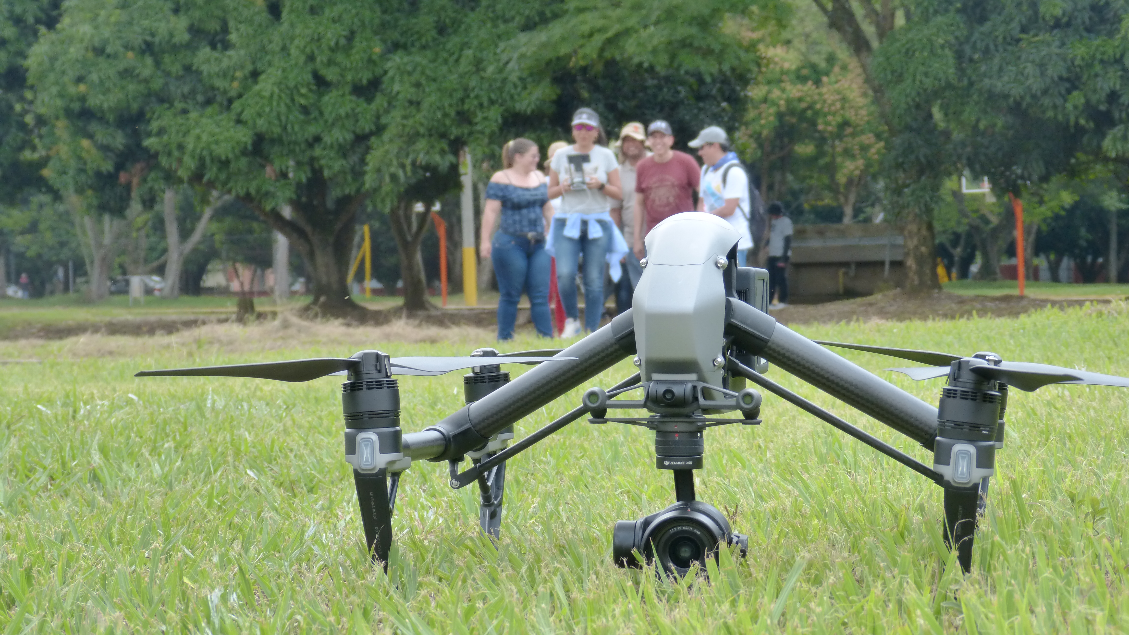 Aeronave tipo drone, localizada en la cancha principal de fútbol de la Universidad del Valle y al fondo el equipo técnico de personas del DAPM.